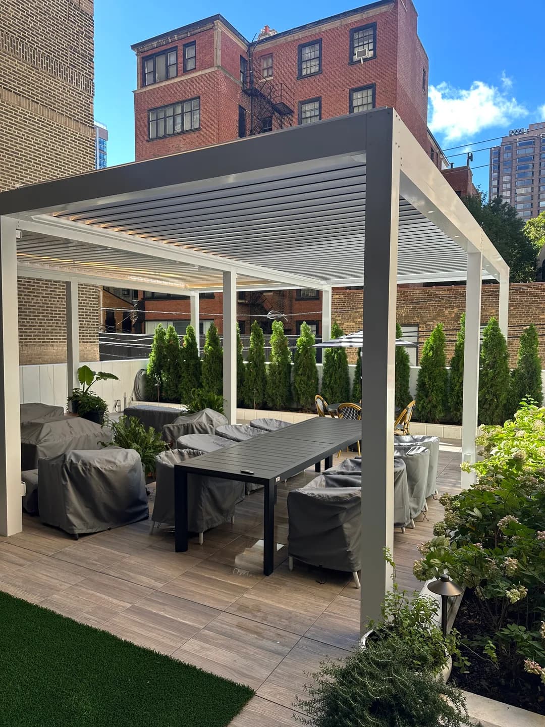 White roof louvers and gray pergola frame above courtyard patio seating